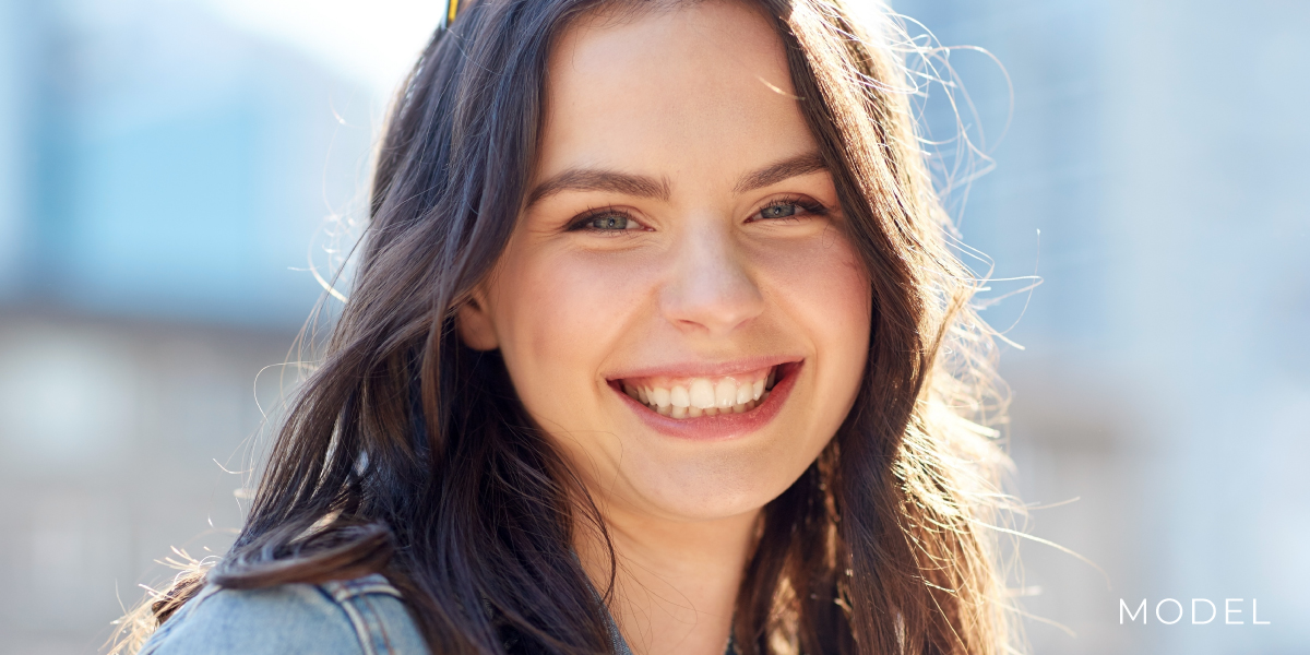 Smiling teenage model outside blue building | perri dermatology