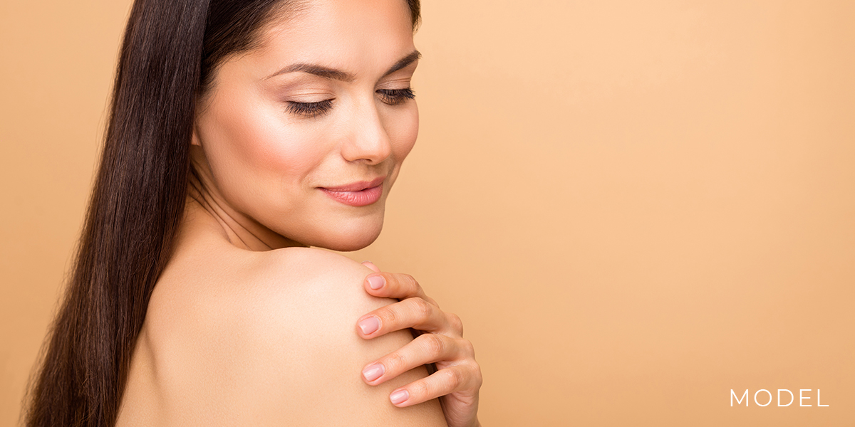 Model Against Orange Background Gripping Shoulder