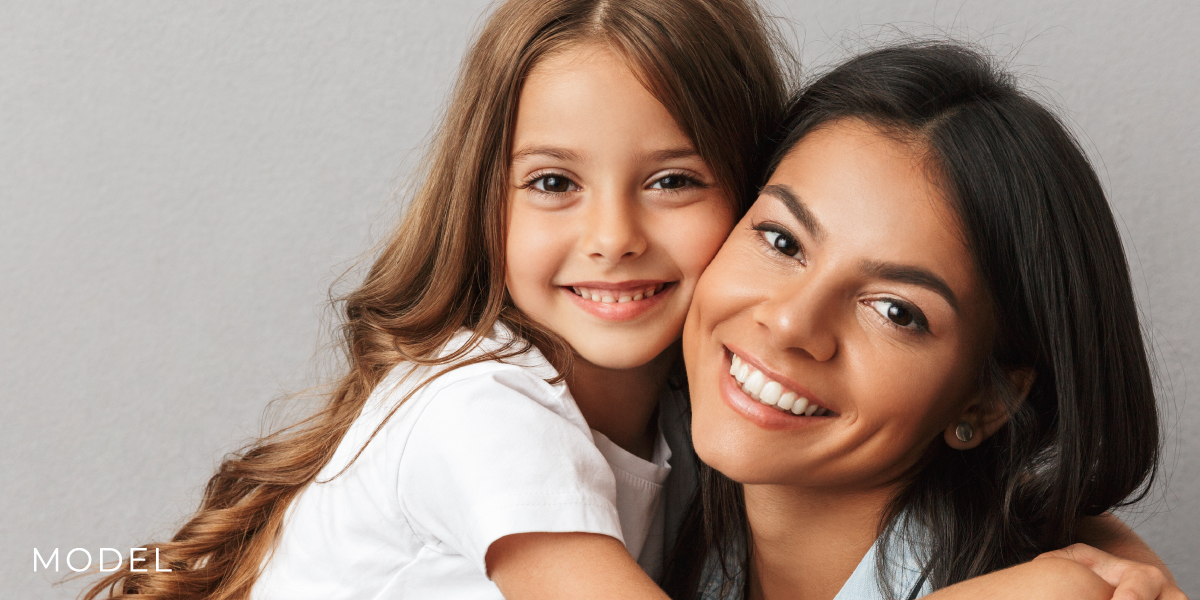 Models Portraying Mom and Daughter Against Gray Background